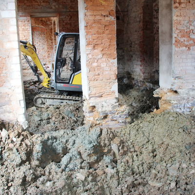 Bild vergrößern: Mitarbeiter des Bauunternehmens Weis sind mit schwerer Technik dabei, den Boden im verbliebenen Erdgeschoß des Nordgebäudes den Boden auszubaggern.