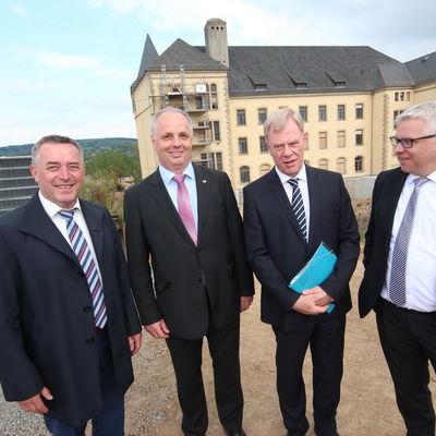 Bild vergr&ouml;&szlig;ern: Ralf Oberdorfer, Prof. Dr. Lutz Neumann, Prof. Dr. Georg Unland und Uwe Gaul (von links) w&auml;hrend des Rundgangs vor dem k&uuml;nftigen Lehrgeb&auml;ude