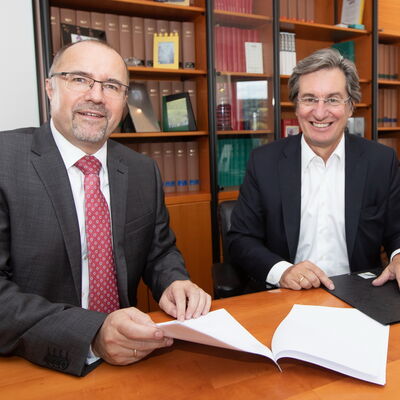 Bild vergrößern: Oberbürgermeister Steffen Zenner (links) und Rainer Gläß, Gründer und CEO der GK Software SE,  beim Unterzeichnen des Kaufvertrags beim Notar.